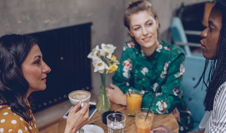 Woman talking with friends and drinking coffe
