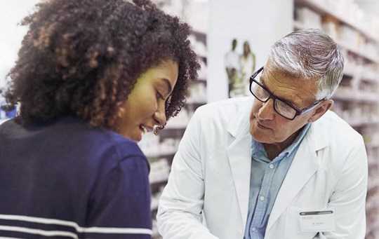 Pharmacist giving a customer prescription meds over the counter